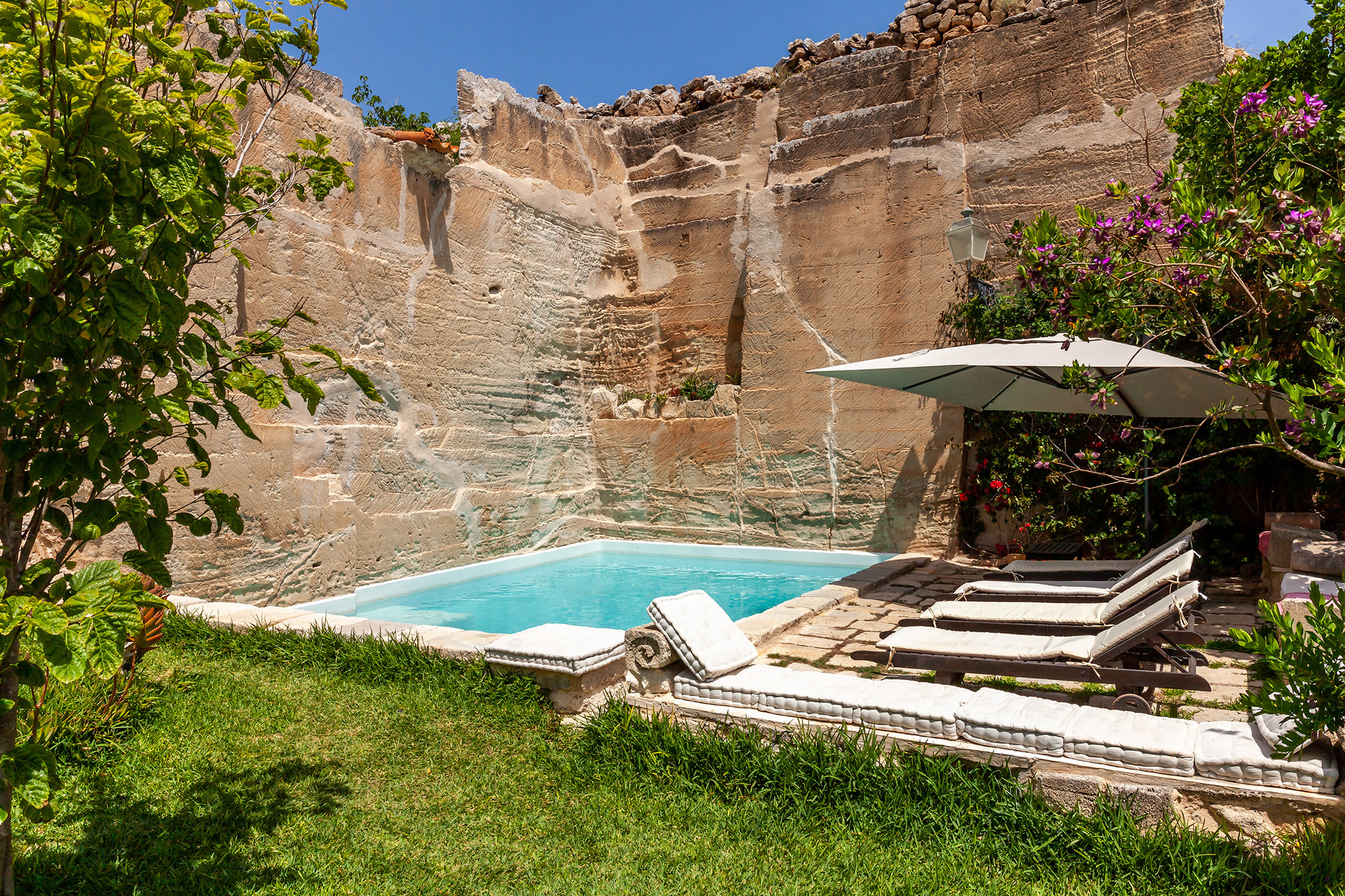 A pool set against a natural rock wall at Zu Nillu, Favignana, Sicily, one of the best villas in Italy with a pool