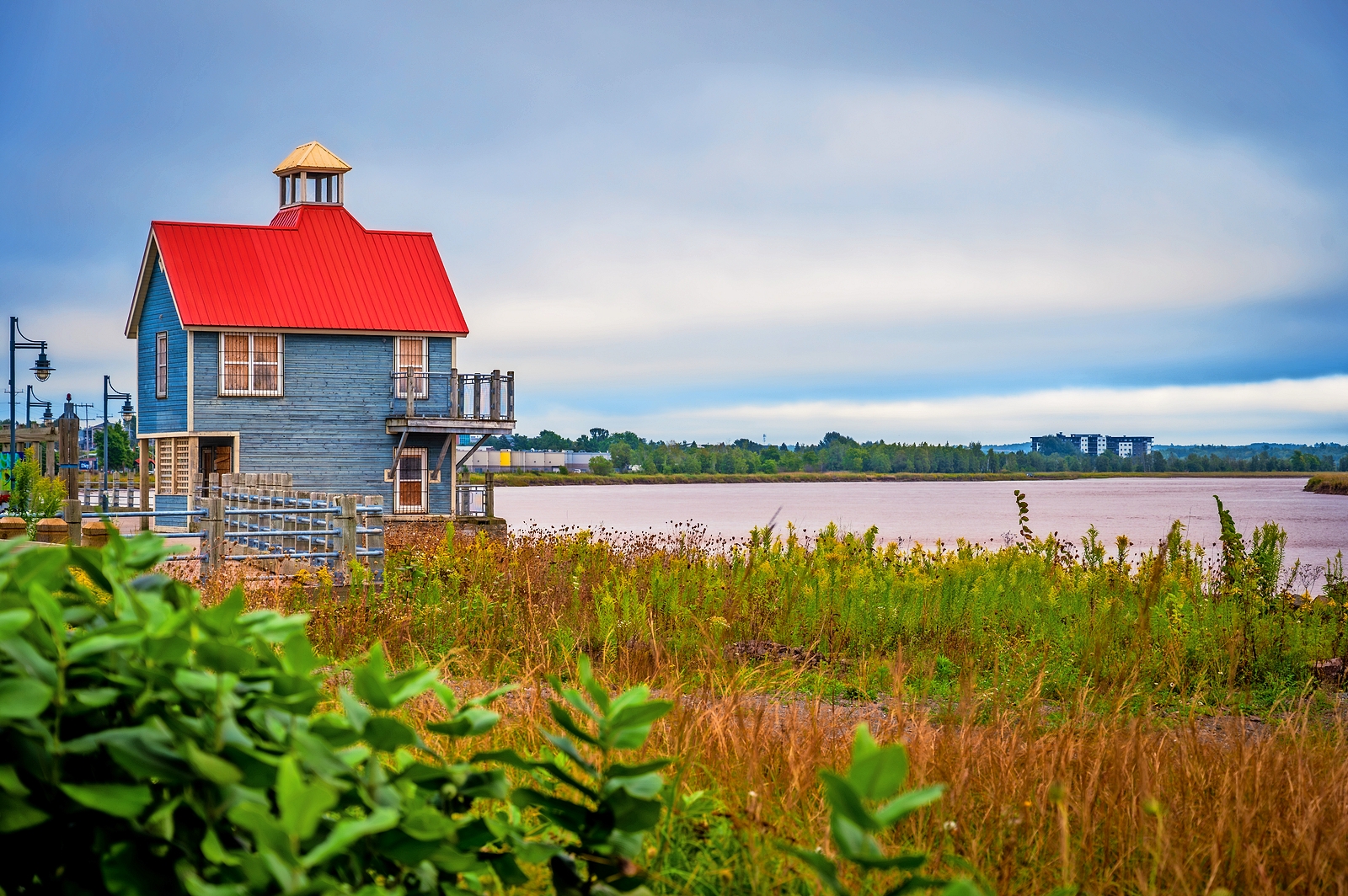 Blue building with red roof by the Petitcodiac River.