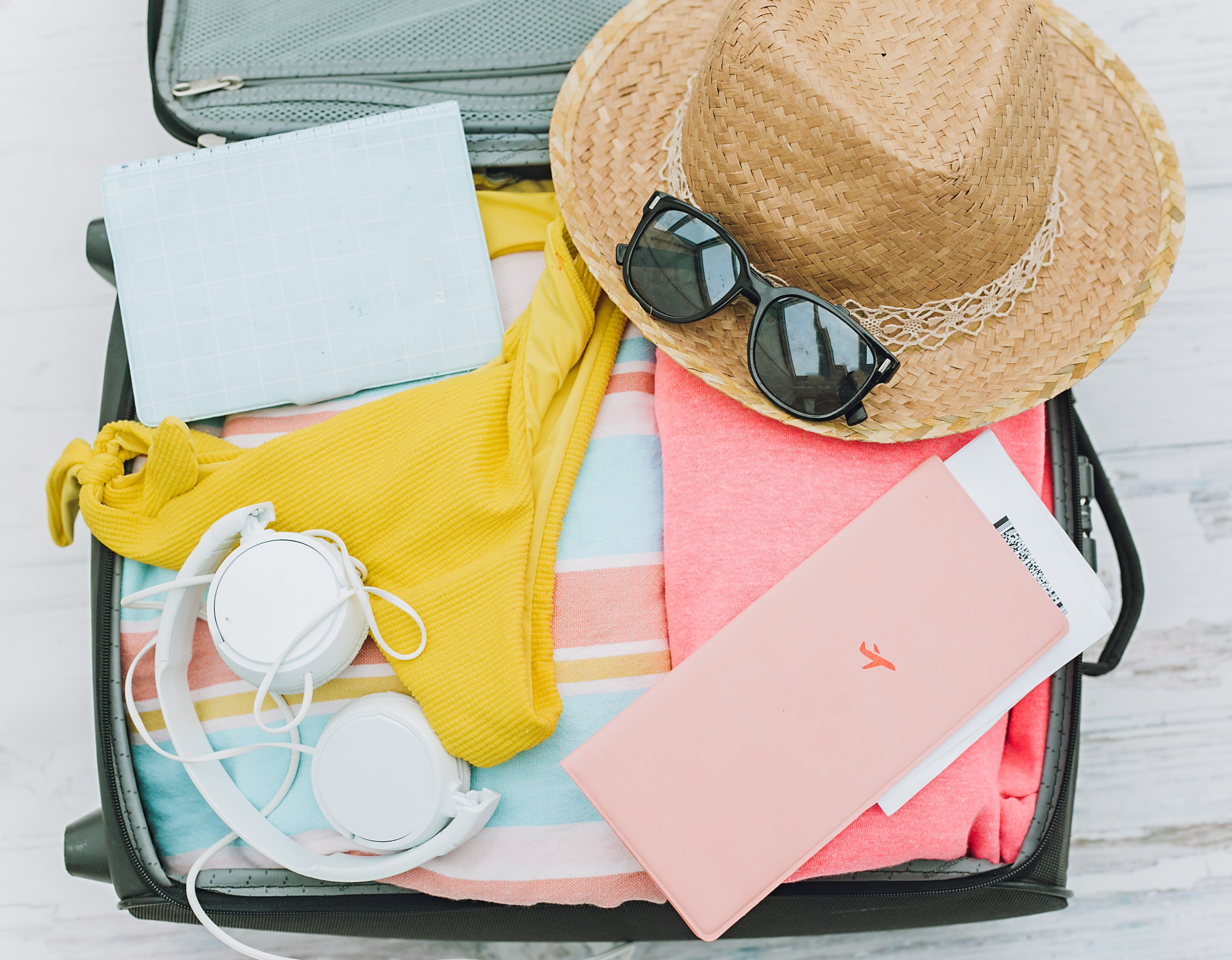 Open suitcase packed with summer travel items.