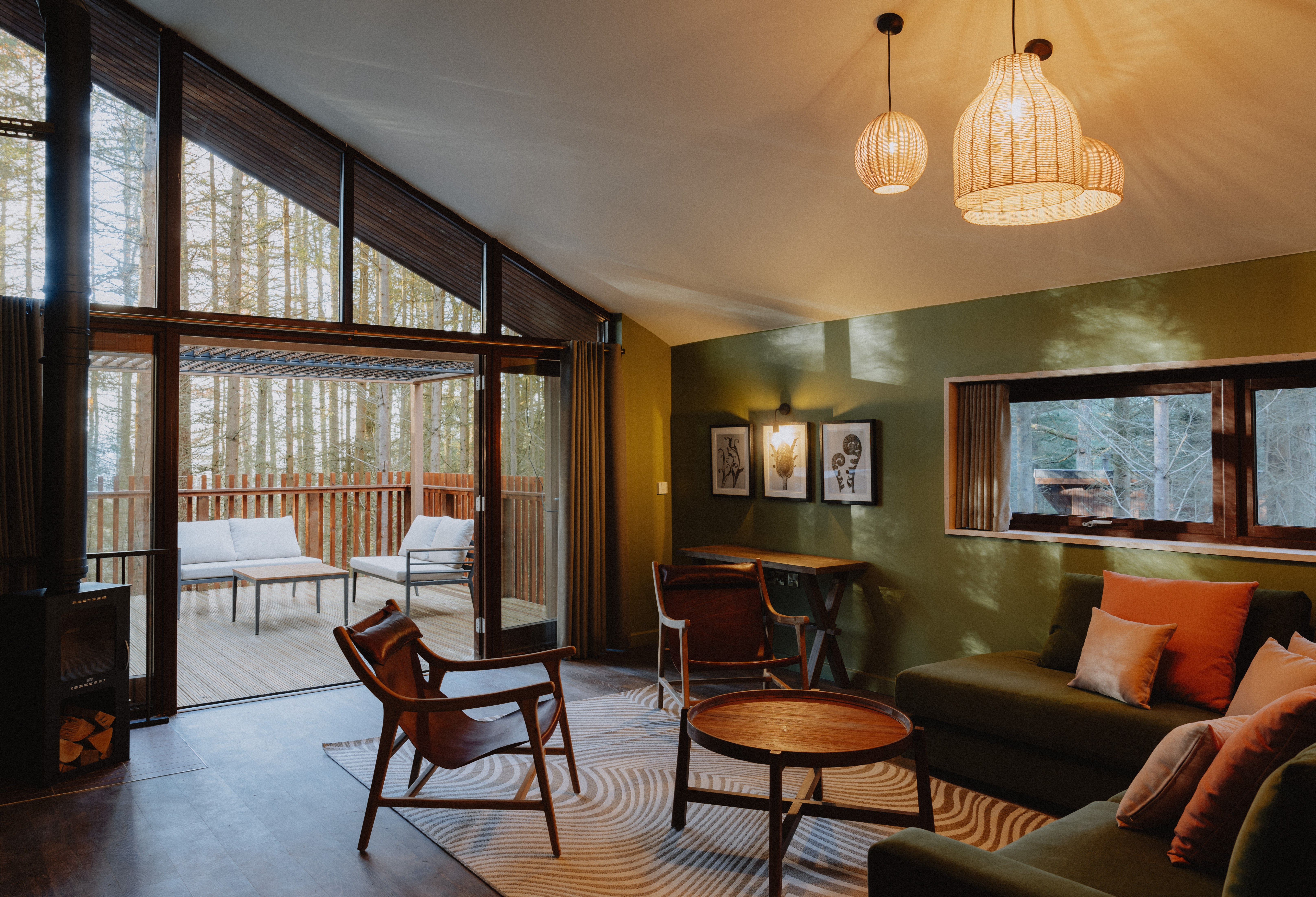 Modern living room with large windows overlooking a forest.