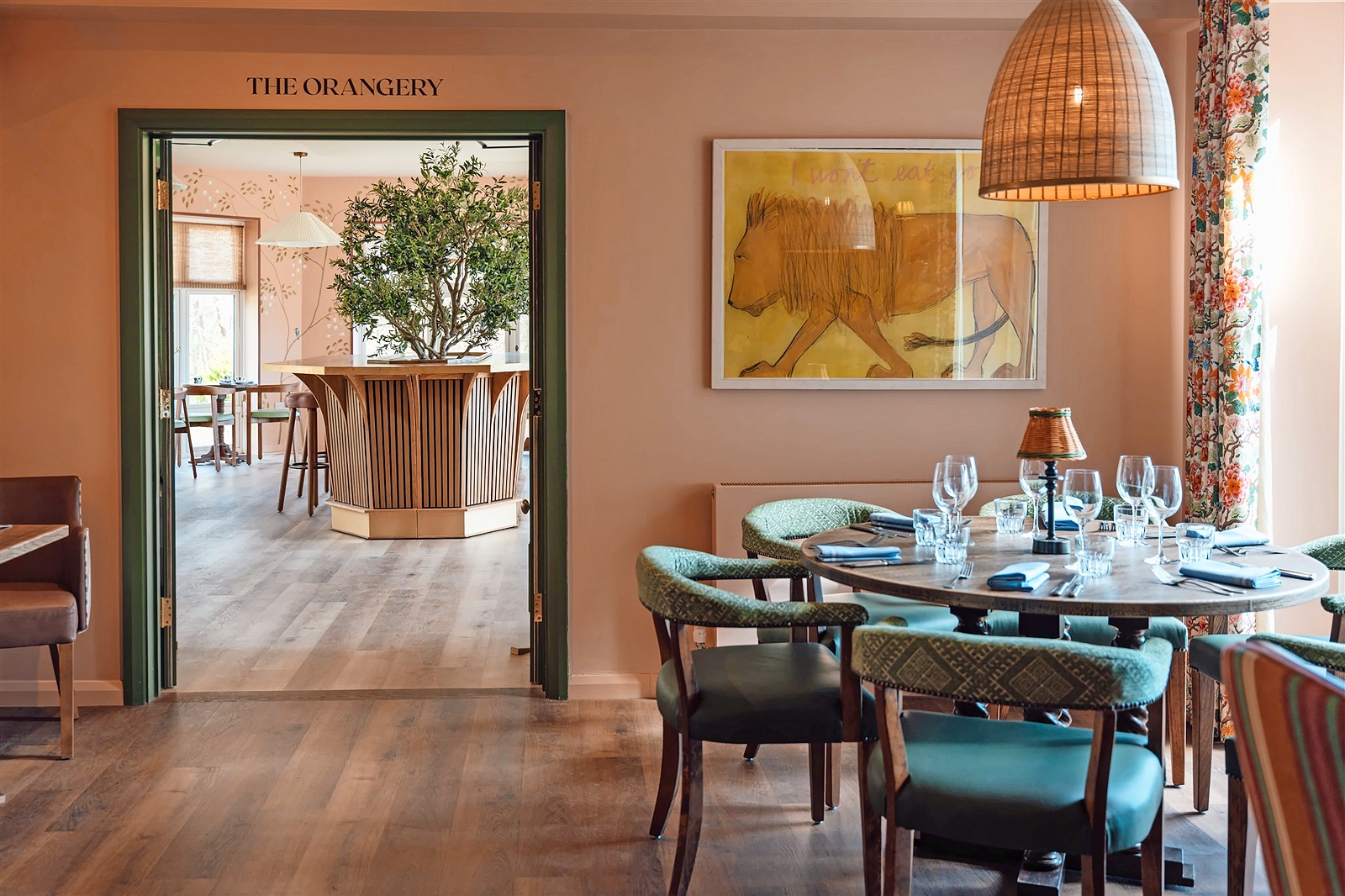 Interior view of a restaurant with a round table set for a meal and a doorway leading to another room.