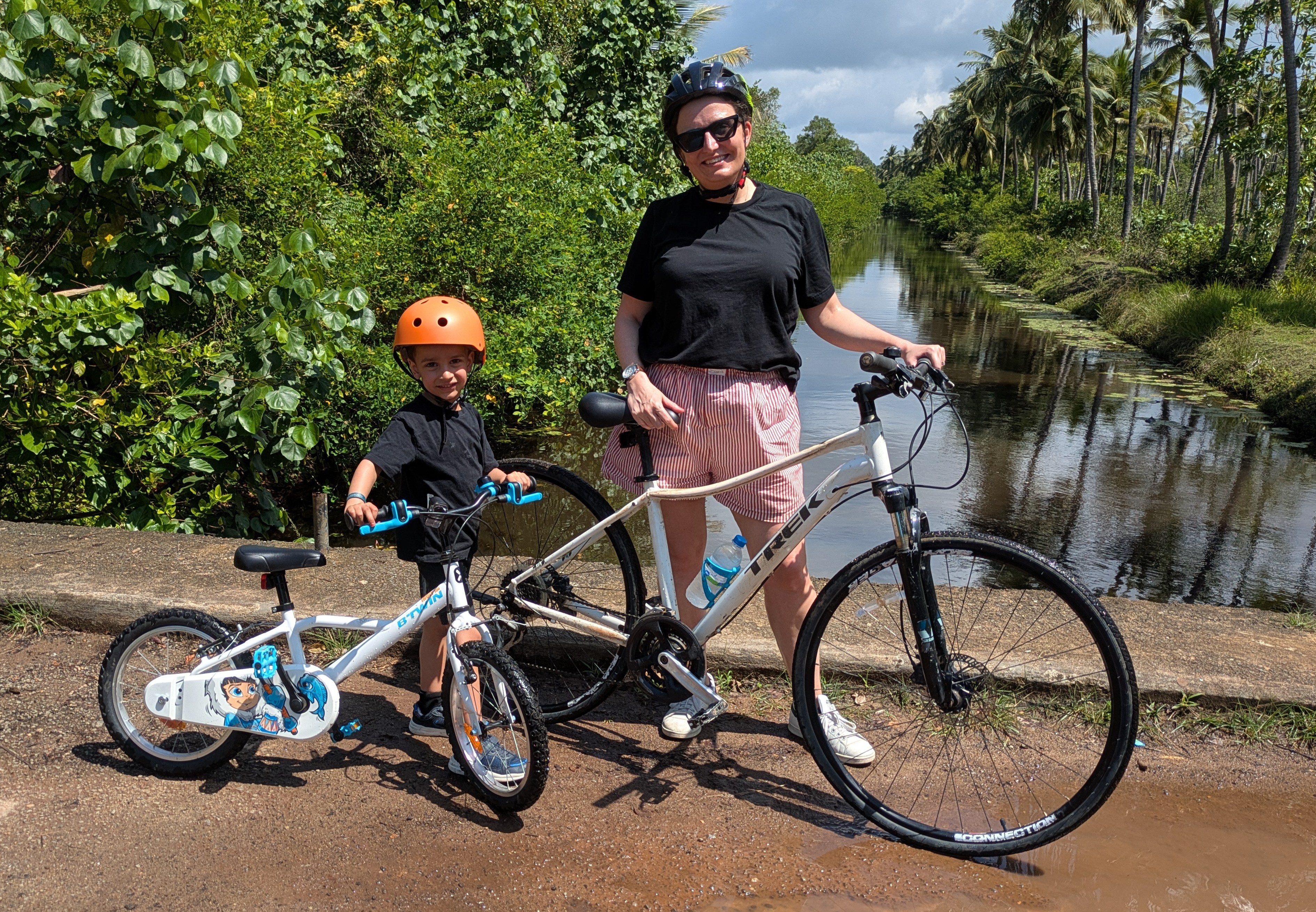 A woman and child on bicycles by a canal.