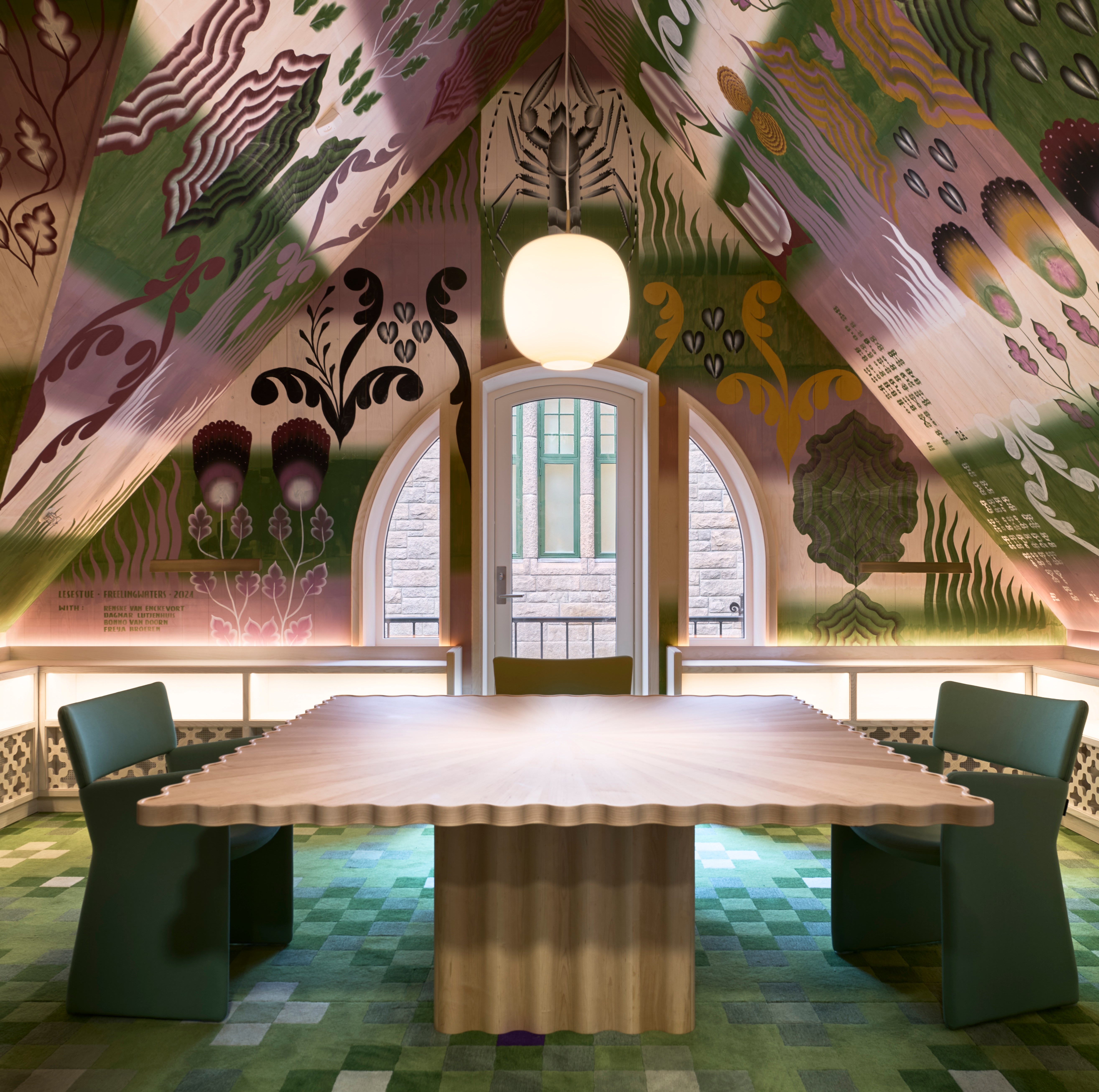 Room with a painted ceiling, a large wooden table, and green chairs.