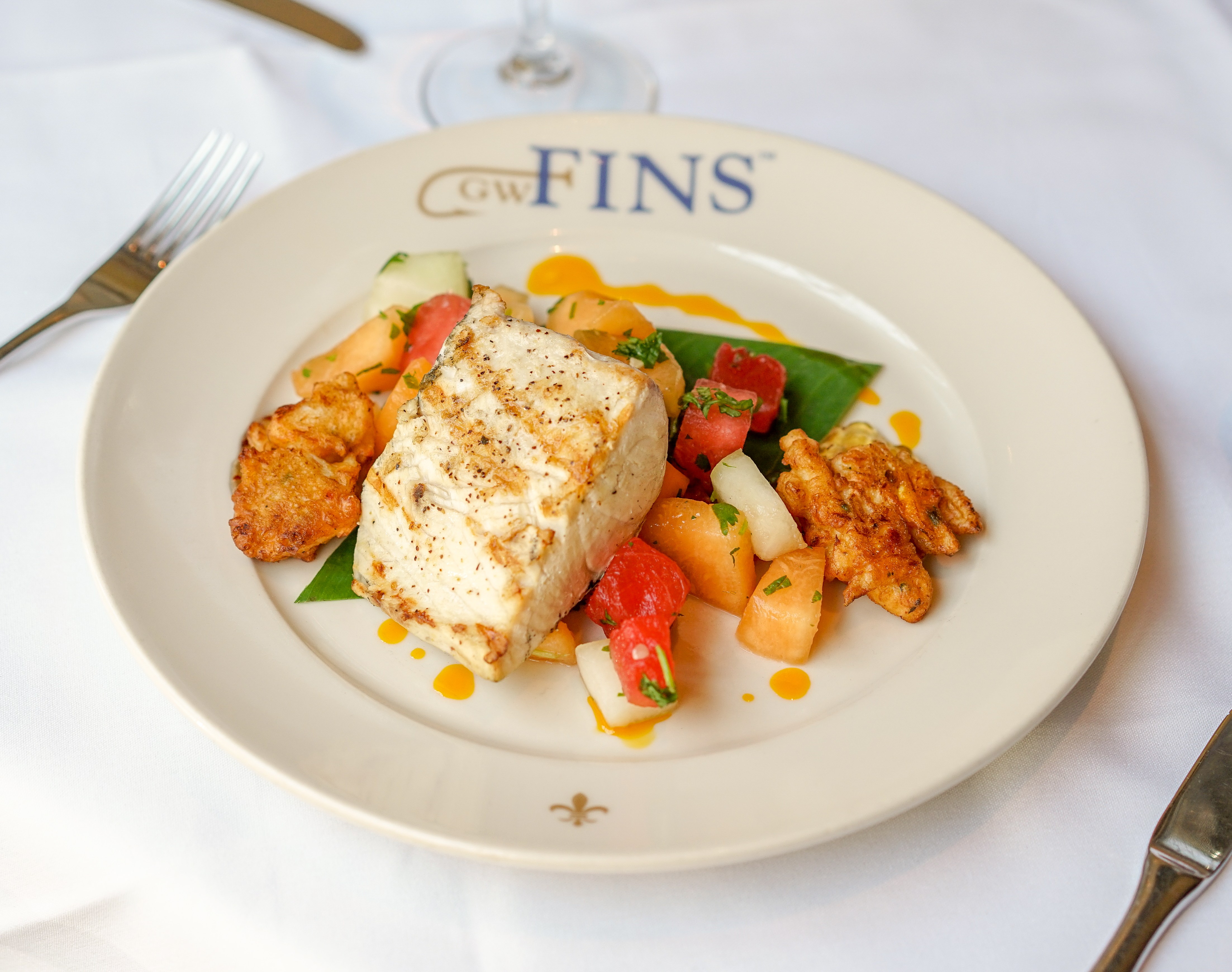 Grilled fish with fruit salad on a plate.