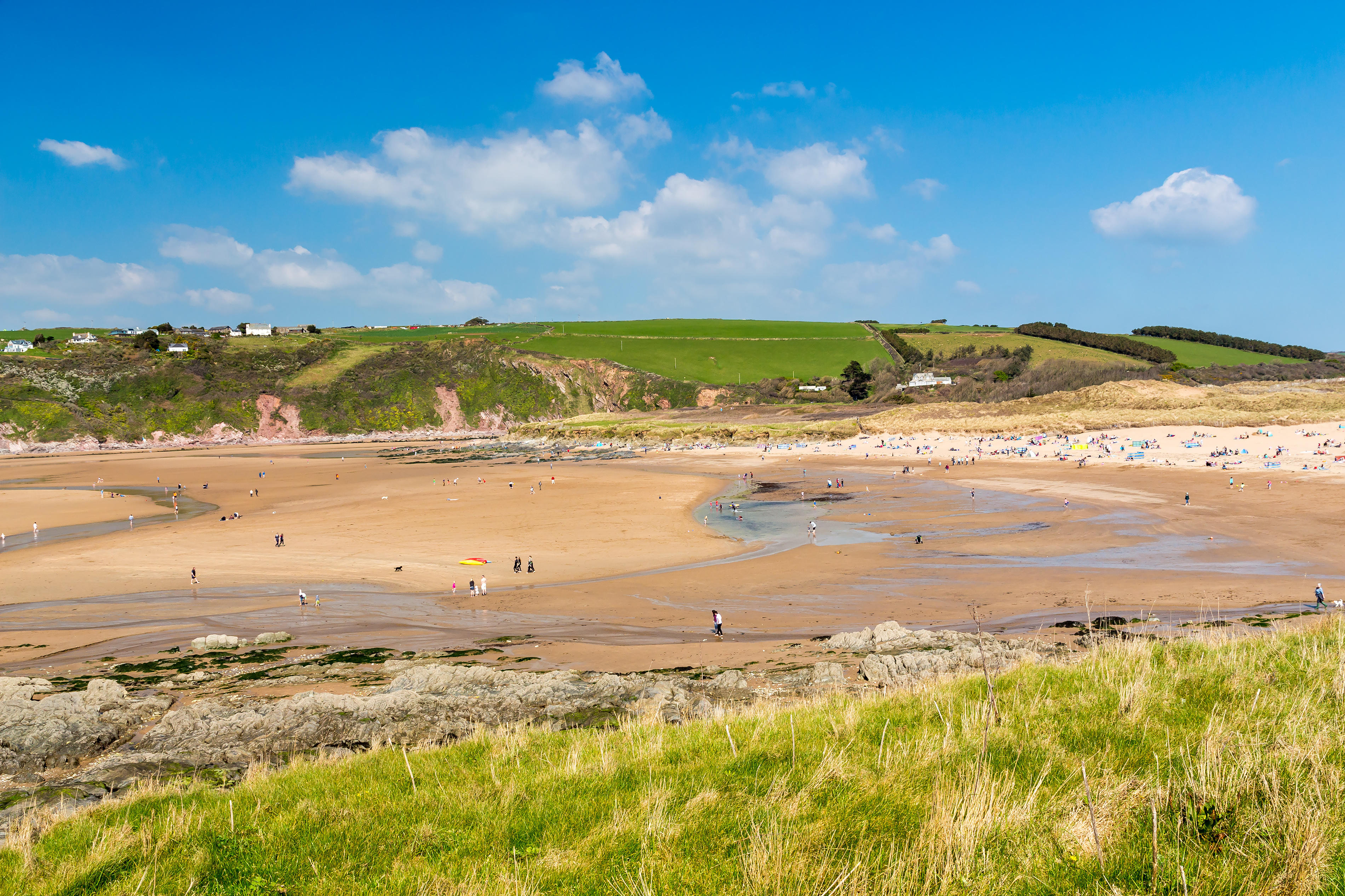Bantham Beach in Devon, England, viewed from above, showing people enjoying the sand and water.