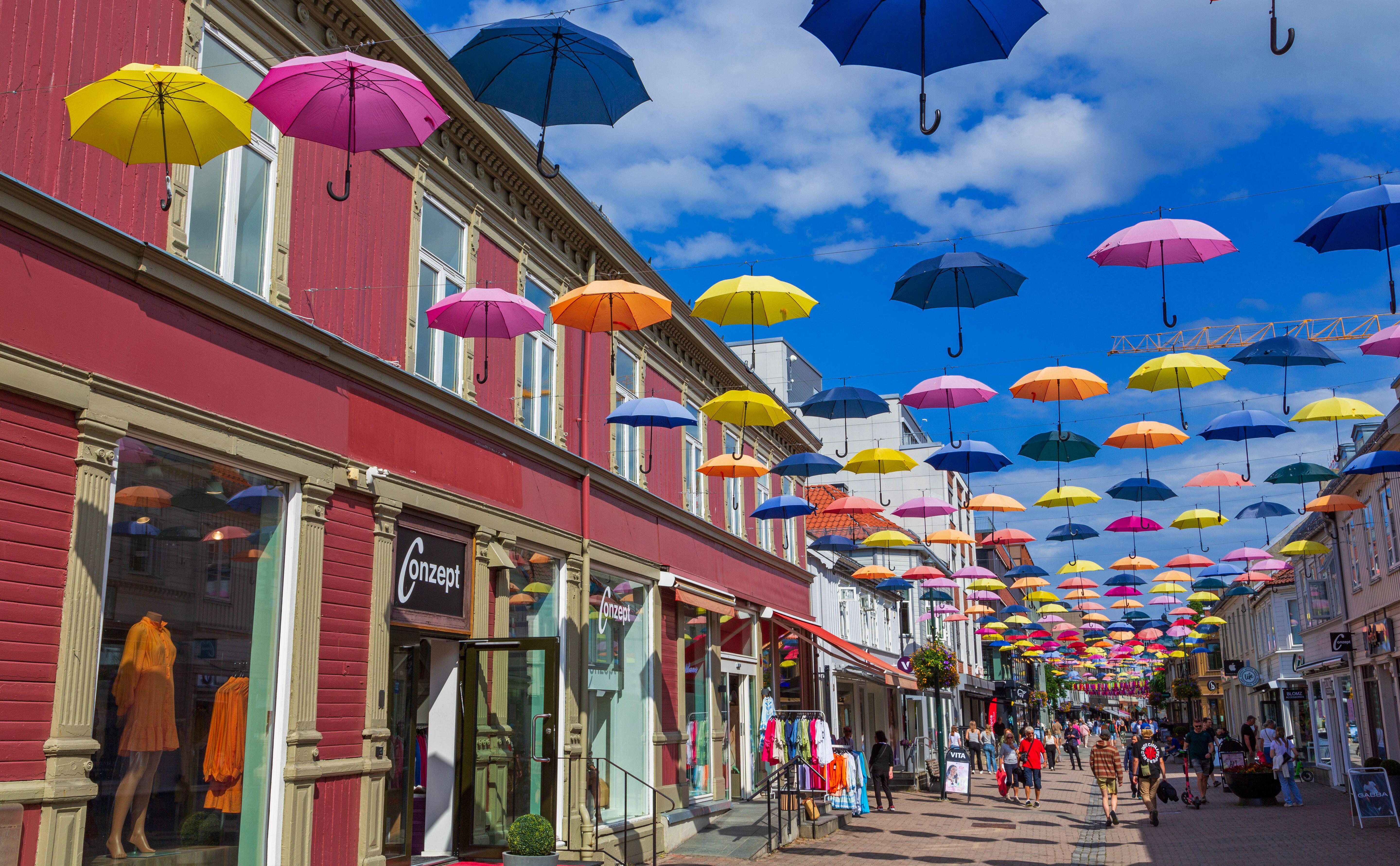 Colorful umbrellas strung above a shopping street in Trondheim, Norway.